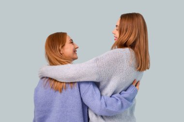 Güzel genç bir kadın mavi arka planda annesine sarılıyor. Uluslararası Sarılma Günü