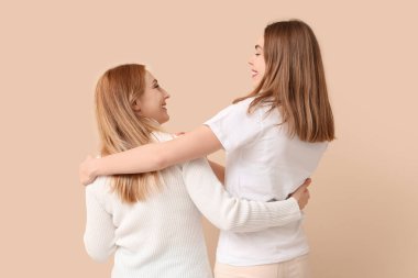 Olgun bir kadın bej arka planda genç kızına sarılıyor. Uluslararası Sarılma Günü