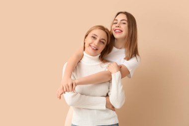 Bej arka planda annesine sarılan güzel bir genç kadın. Uluslararası Sarılma Günü