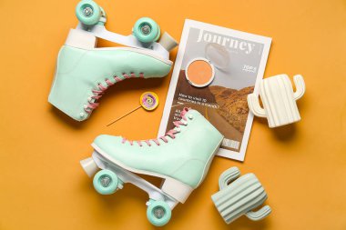 Turuncu arka planda bir çift eski paten, dergi ve kozmetik ile kompozisyon