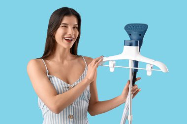 Mavi arka planda modern giysili buharlı güzel bir kadın.