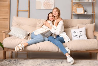 Evdeki kanepede sarılan genç kadınlar.