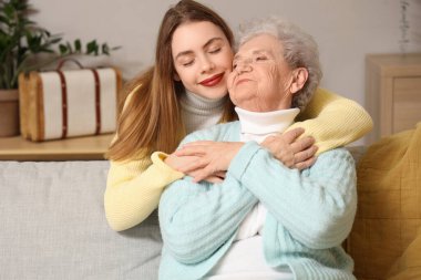 Evde büyükannesine sarılan genç bir kadın.