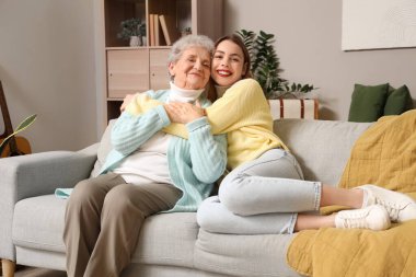 Evdeki kanepede büyükannesine sarılan genç kadın.