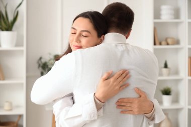 Evinde kocasına sarılan mutlu genç bir kadın.