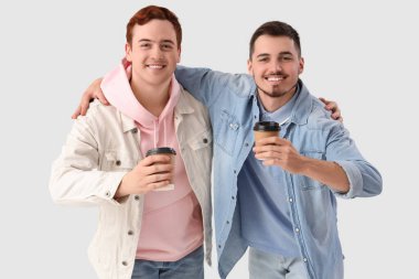 Kahve fincanları olan erkek arkadaşlar beyaz arka planda sarılıyorlar.