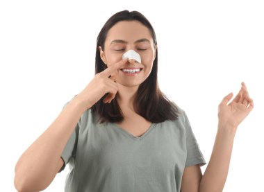 Beyaz arka plandaki sargılı burnu gösteren genç bir kadın. Estetik ameliyat konsepti