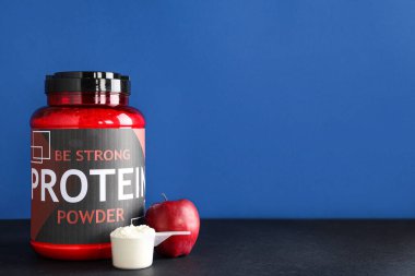 Renk arkaplanına karşı protein tozu, kepçe ve elma şişesi