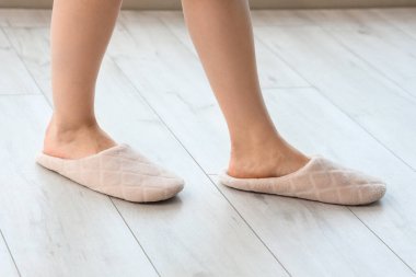 Evdeki lamine zeminde yumuşak terlikli bir kadın, yakın plan.