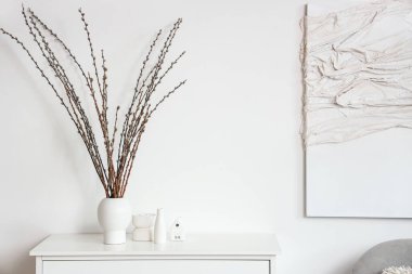 Hafif oturma odasında klozette söğüt dalları olan vazo.