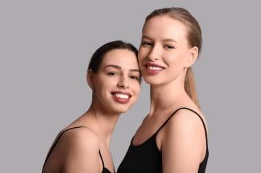 Gri arka planda gülümseyen genç kız kardeşler