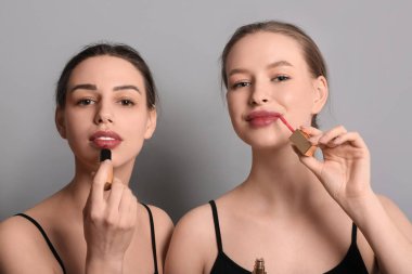 Gri arka planda makyaj yapan kız kardeşler.