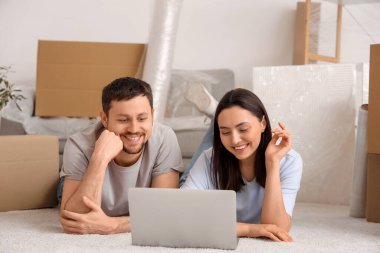 Genç çift yeni dairelerinde dizüstü bilgisayar kullanıyor.