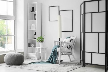 Lambası, koltuğu ve raf ünitesi olan bir oturma odası.