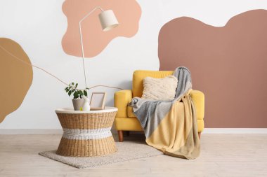 Oturma odasının içinde lamba, koltuk ve masa var.