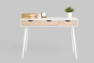 Beyaz arka planda kitaplar ve bitki örtüsü olan şık bir masa