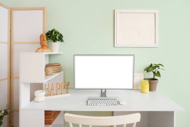 Modern bilgisayarlı şık bir masa. Odada turkuaz duvar var.