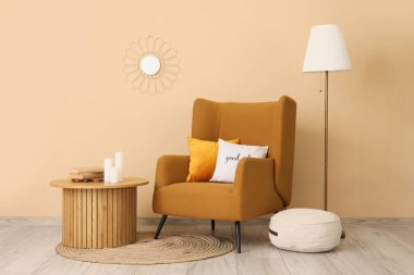 Standart lamba ve bej duvarın yanında kahve masası olan şık kahverengi koltuk.