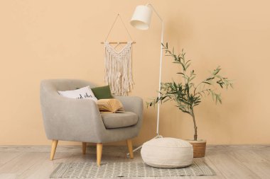 Standart lamba ve bej duvarın yanındaki çiçek desenli gri koltuk.