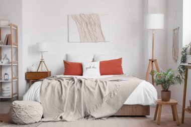 Rahat yatağı, yatağı, yatağı ve lambası olan modern yatak odasının içinde.