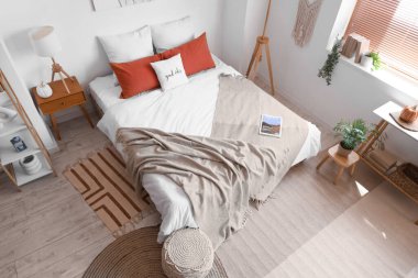 Rahat yataklı, komodinli modern yatak odası ve puf.