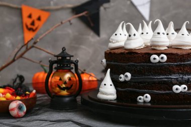 Tatlı Cadılar Bayramı pastası Gri arka planda kremalı hayaletler, şekerler, gözler ve fenerle süslenmiş