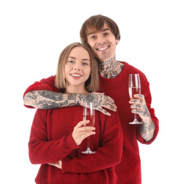Kırmızı kazaklı mutlu genç çift beyaz arka planda şampanya bardakları tutuyor. Noel kutlaması