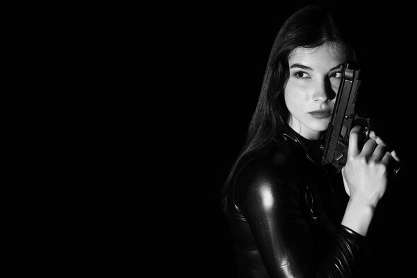 Female spy with gun on dark background, closeup