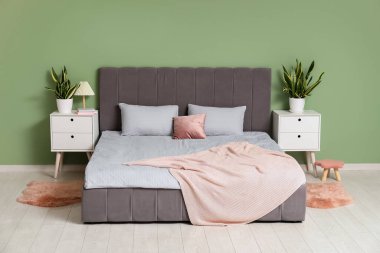 Şık bir yatak odası, yatağı, komodinleri ve çiçekleri var.