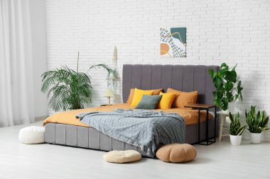 Yatak odası, çiçekleri ve komodinleri olan rahat bir oda.