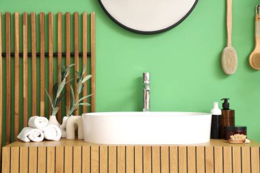 Lavabo, çekmeceler ve banyodaki yeşil duvarın yanındaki katlanan ekran.