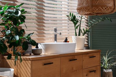 Modern lavabo, ev bitkileri ve banyo malzemeleri banyo penceresinin yanındaki çekmecelerde.