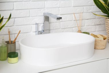 Modern lavabo, banyo malzemeleri ve banyodaki beyaz tuğla duvarın yanındaki çekmeceler.