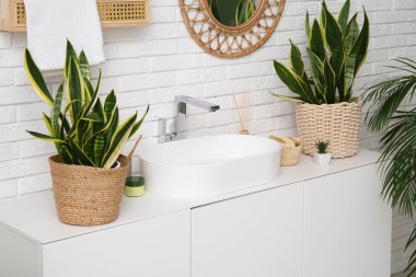 Modern lavabo, banyo malzemeleri ve çekmecelerde beyaz tuğla duvarın yanında banyo malzemeleri.