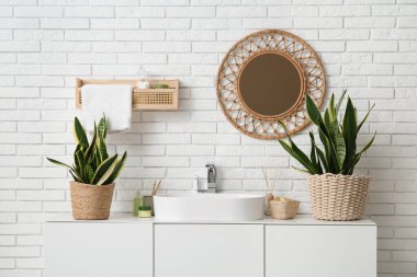 Modern lavabo, banyo malzemeleri ve çekmecelerde beyaz tuğla duvarın yanında banyo malzemeleri.