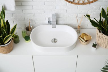 Modern lavabo, banyo malzemeleri ve çekmecelerde beyaz tuğla duvarın yanında banyo malzemeleri.