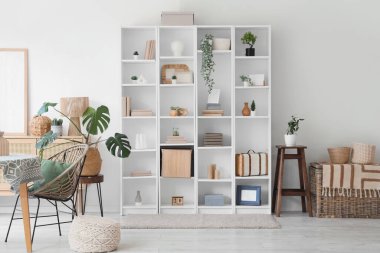 Büyük raf ünitesi ve ev bitkileriyle modern oturma odasının içinde.