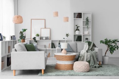 Gri koltukları, raf ünitesi ve ev bitkileriyle modern oturma odasının içinde.