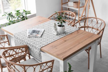 Mutfakta sandalyeler ve bitkiler olan şık bir masa.