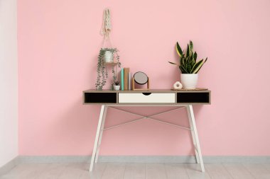 Aynalı, çiçekli ve pembe duvarlı şık bir masa.