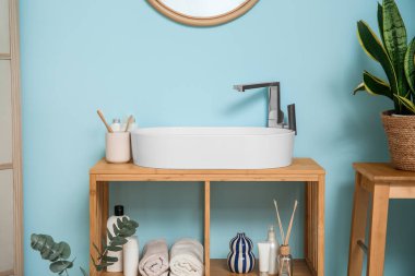 Banyoda banyo aksesuarları olan beyaz seramik lavabo ve raf ünitesi.