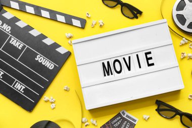 Sözcüklü film alkışları, sinema biletleri ve sarı arka planda film makarası.