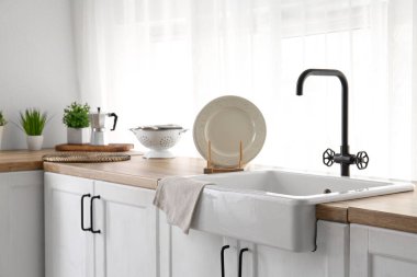 Güzel mutfağın penceresinin yanındaki ahşap tezgahta lavabo