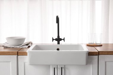 Şık mutfakta pencerenin yanındaki ahşap tezgahta lavabo.