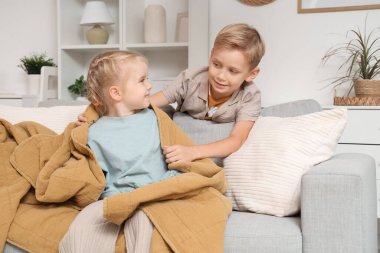 Küçük çocuk evde kız kardeşine ekose veriyor.