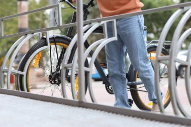 Bisikleti park eden genç adam şehir caddesindeki bisiklet parkında.