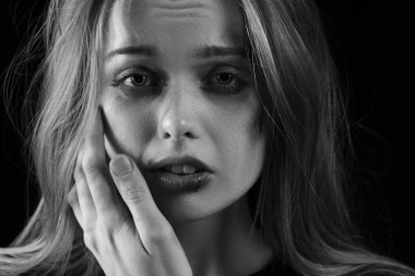 Siyah beyaz portre, arka planda ağlayan yaralı bir kadının resmi. Aile içi şiddet kavramı