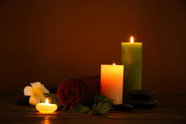 Havlulu spa kompozisyonu ve koyu ahşap masada yanan mumlar.