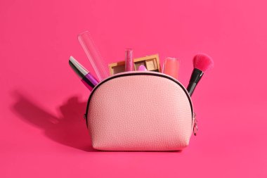 Pembe arka planda dekoratif kozmetik ve aksesuarlı çanta