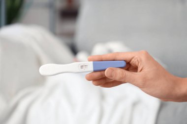 Odada hamilelik testi pozitif çıkmış bir kadın eli var. Yakın çekim.